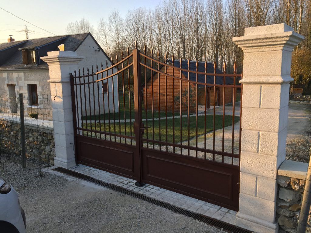 Portail marron avec poteaux en pierres blanches