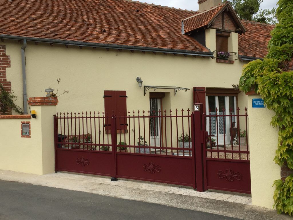 Grand portail et portillon rouge assorti aux volets de la maison