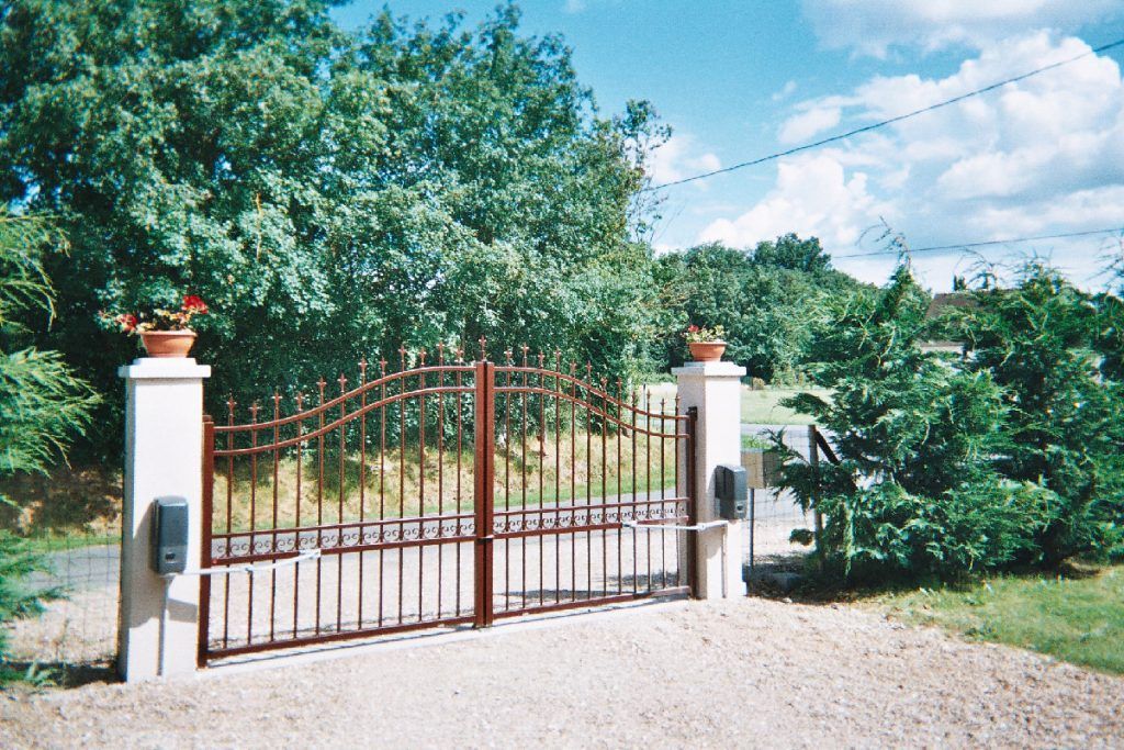 Portail avec des poteaux de chaque côté surplombant des pots de fleurs