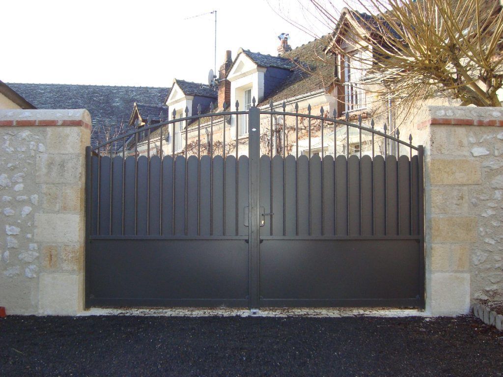 Portail en fer accroché à un muret en pierre