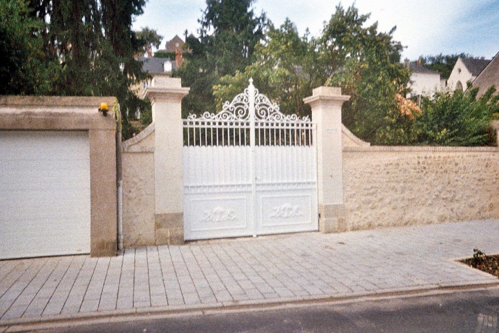 Portail blanc avec arabesques en haut