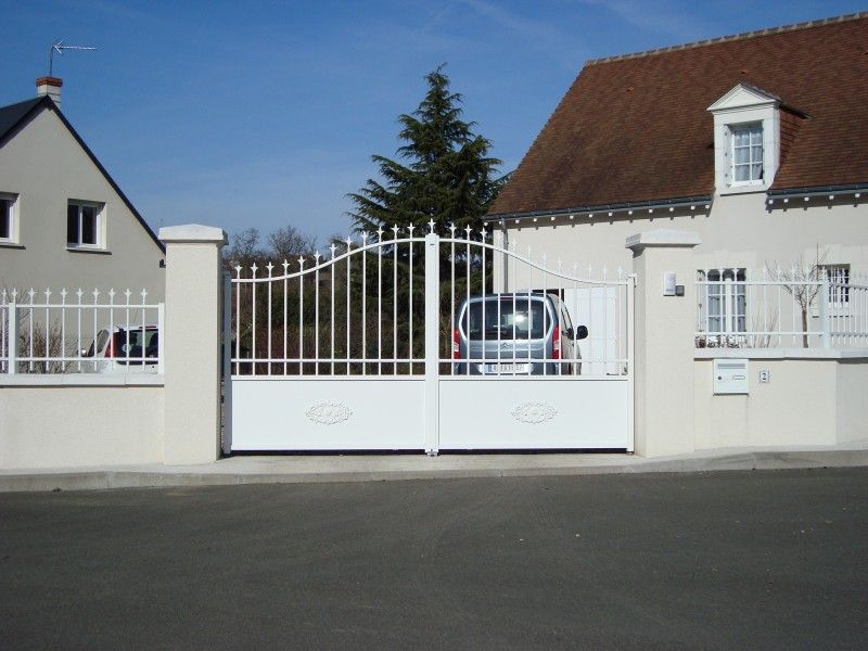 Voiture derrière un portail en fer blanc assorti à la clôture