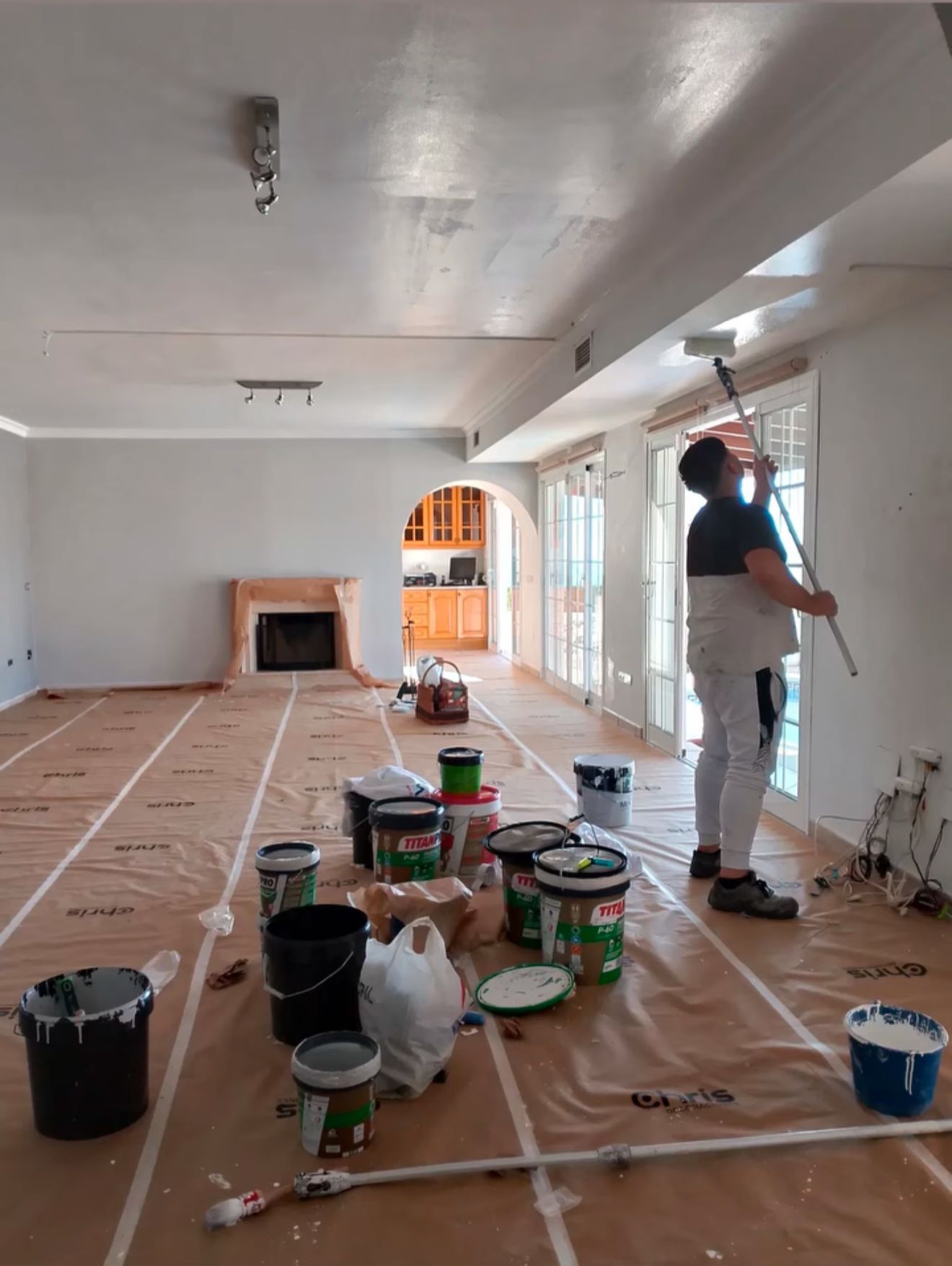 Un hombre está pintando una pared al lado de una ventana.