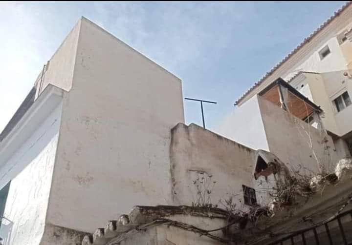 Un edificio blanco con una antena en la azotea.