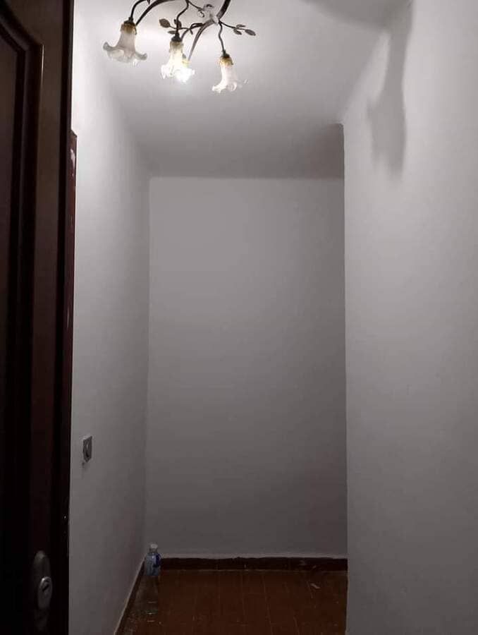 Un pasillo con paredes blancas y una lámpara de araña colgando del techo.