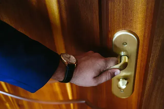Un hombre que lleva un reloj está abriendo una puerta.