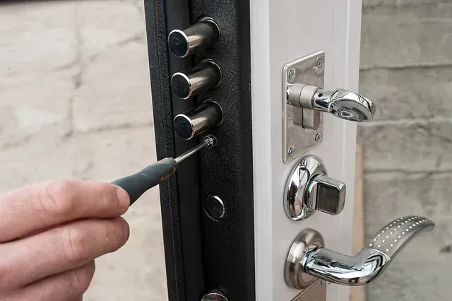 Una persona está arreglando una cerradura de puerta con un destornillador.