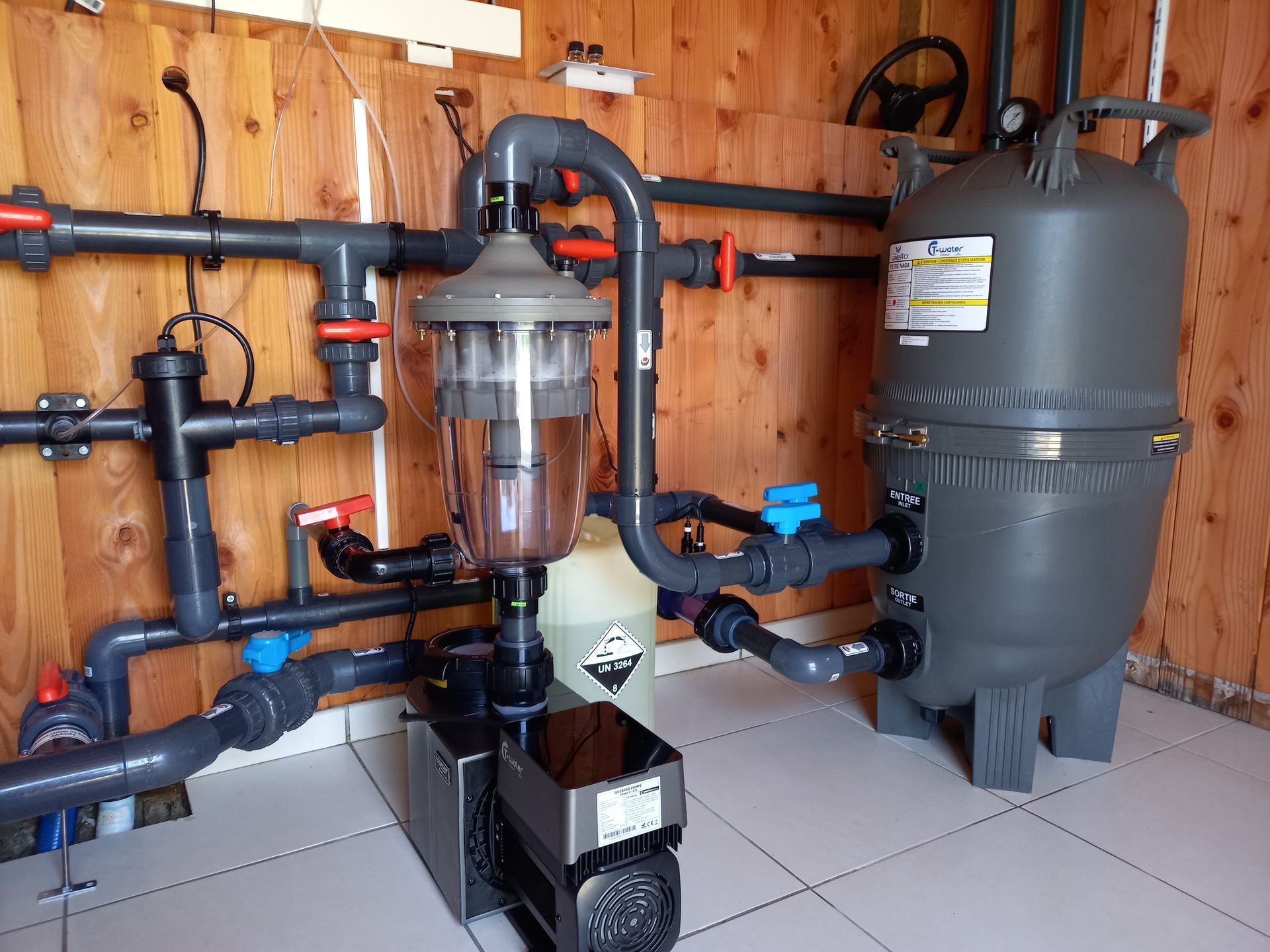 Système de filtration de piscine avec pompe, réservoir de filtre et tuyauterie contre les panneaux de bois.