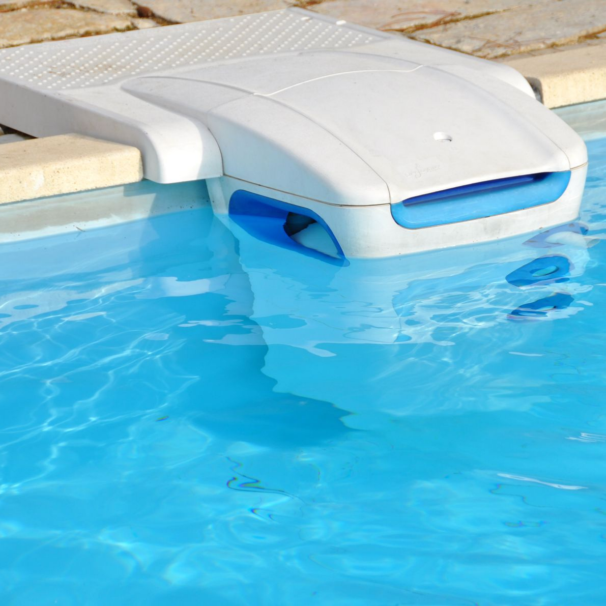 Écumoire de piscine blanc et bleu flottant dans l'eau claire et bleue de la piscine.