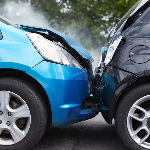 Ein blaues Auto kollidierte frontal mit einem dunklen Auto, wobei beide Frontpartien auf der Straße völlig zerstört wurden.