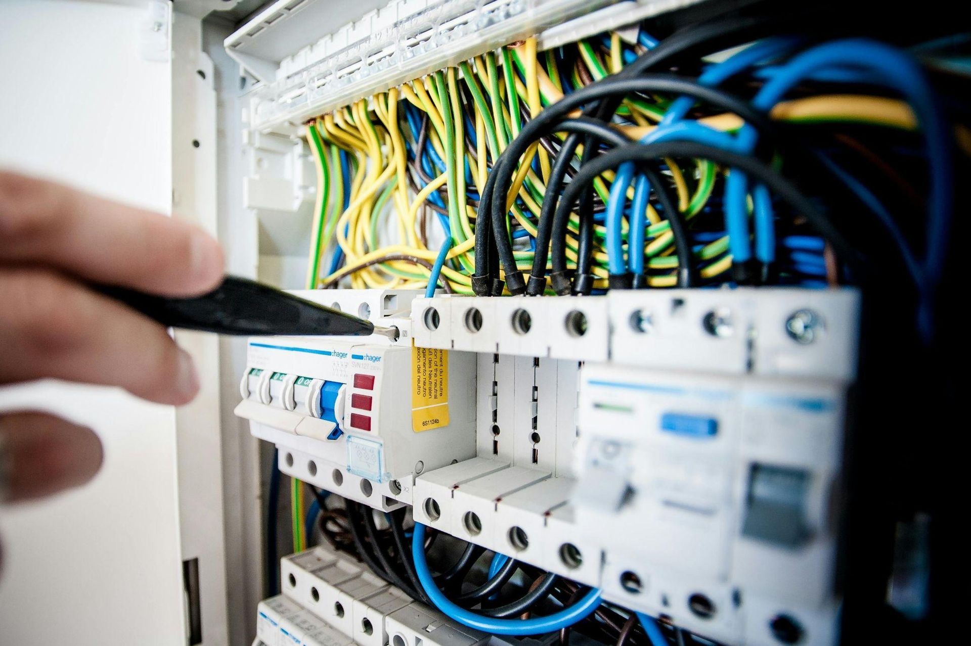 Una persona está trabajando en una caja eléctrica con un destornillador.