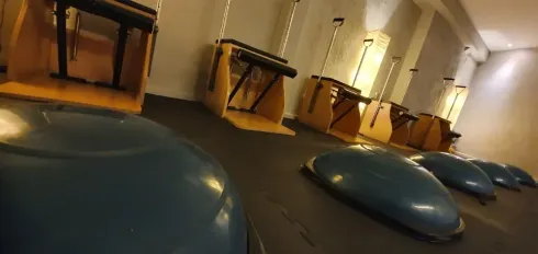 Estudio de Pilates con entrenadores de equilibrio de color verde azulado y equipos de Pilates de color amarillo.