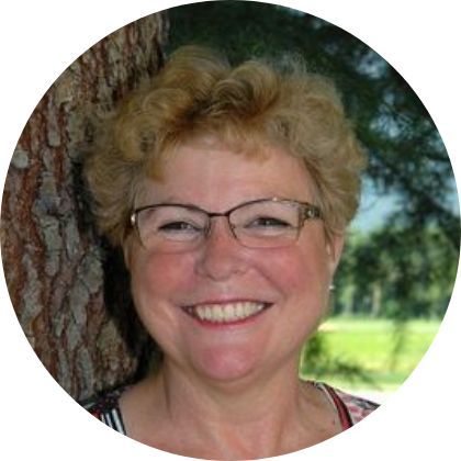 Eine Frau mit Brille lehnt lächelnd an einem Baum. Ladinas Reinigungen GmbH