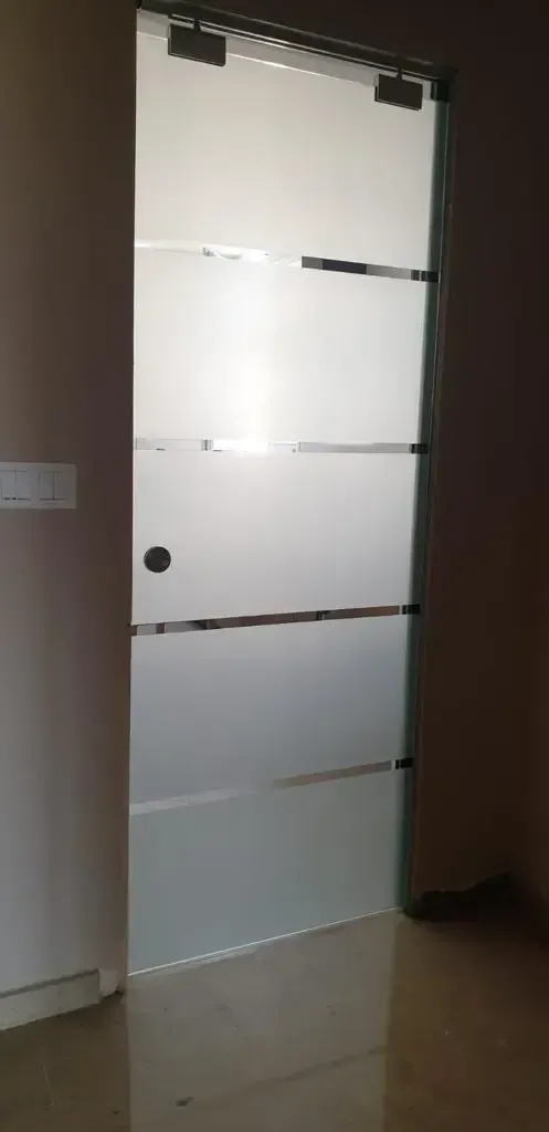 Una moderna puerta interior de vidrio esmerilado con cuatro molduras metálicas horizontales, enmarcada en un sencillo marco.