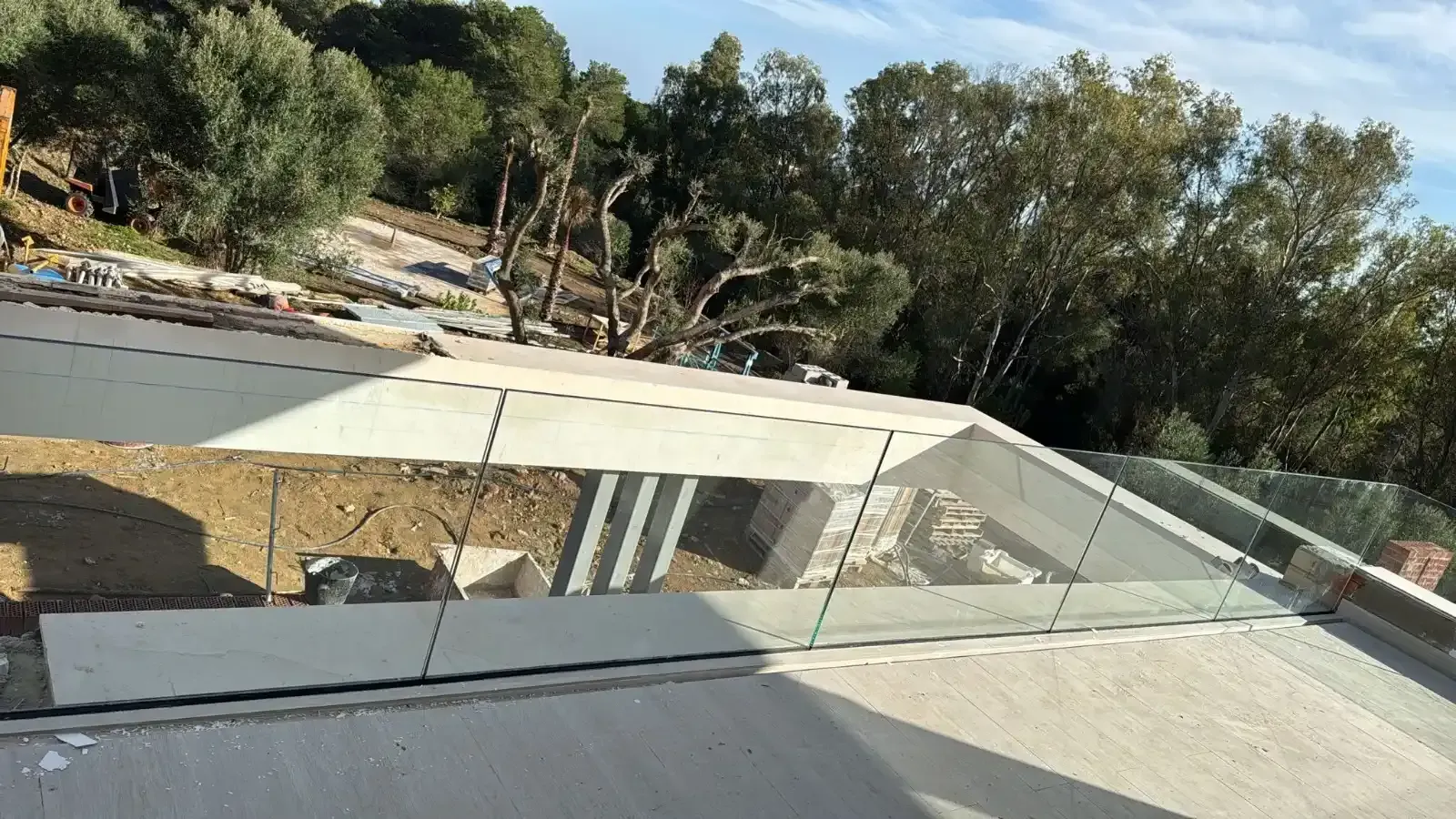 Una barandilla de vidrio sin marco instalada en el borde de un balcón de hormigón.