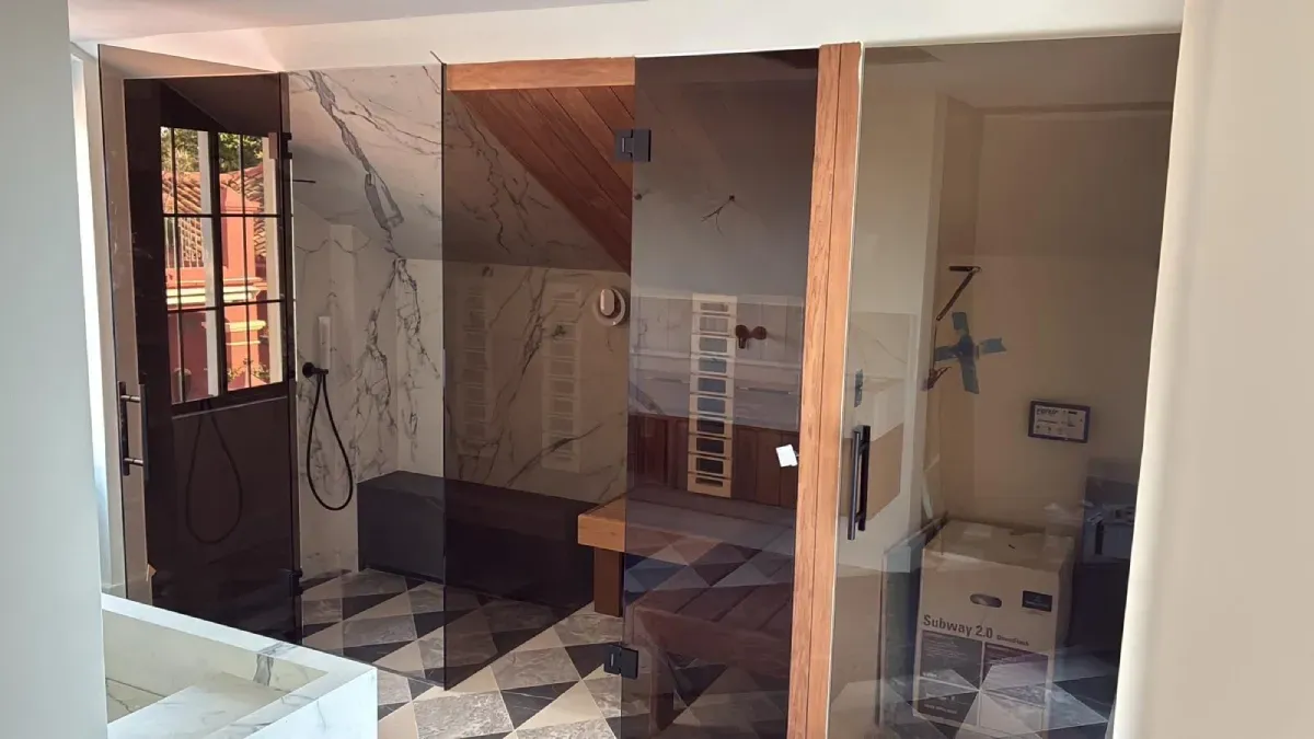 Una sauna con techo y banco de madera, puerta de vidrio