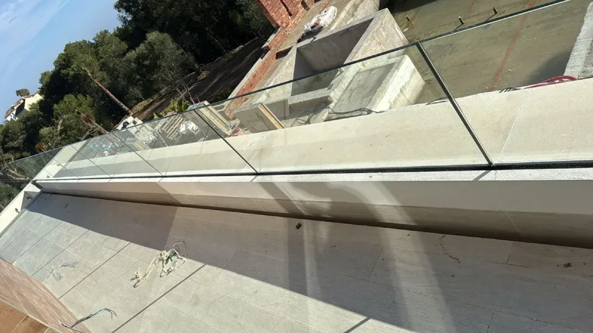 Barandilla de cristal sin marco con base de hormigón sobre una terraza