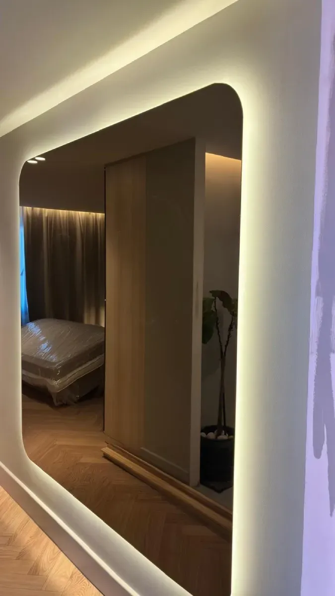 Un espejo rectangular de pared con esquinas redondeadas e iluminación LED cálida integrada