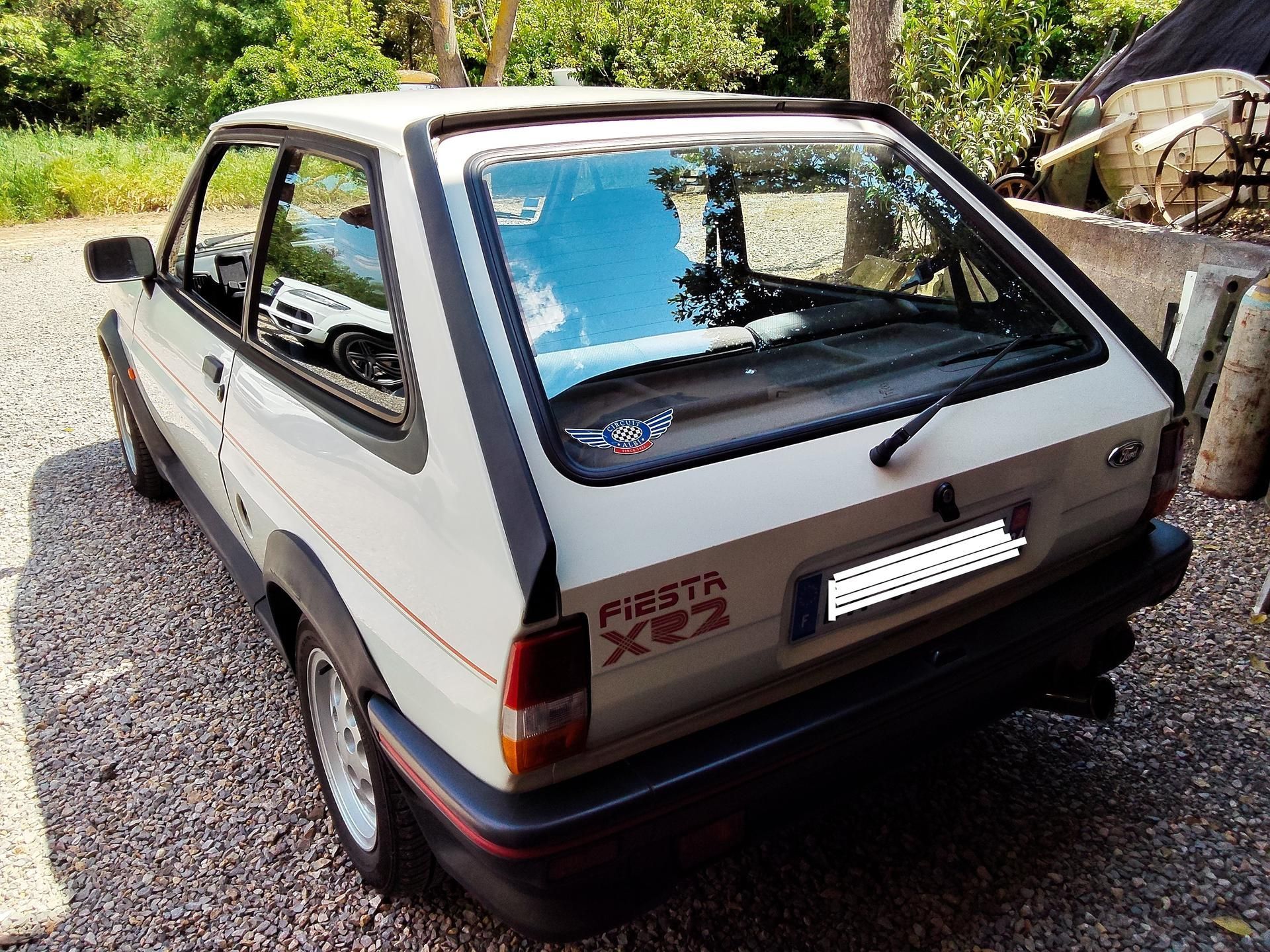 Ford Fiesta XR2 blanche garée sur du gravier.