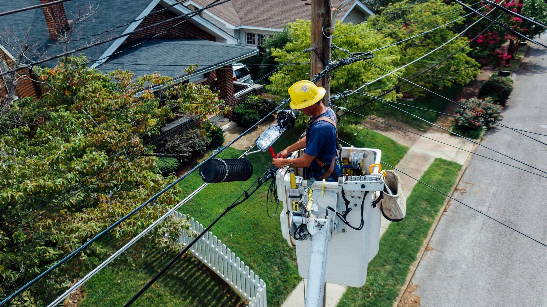 Una vista aérea de un hombre en un balde trabajando en líneas eléctricas.