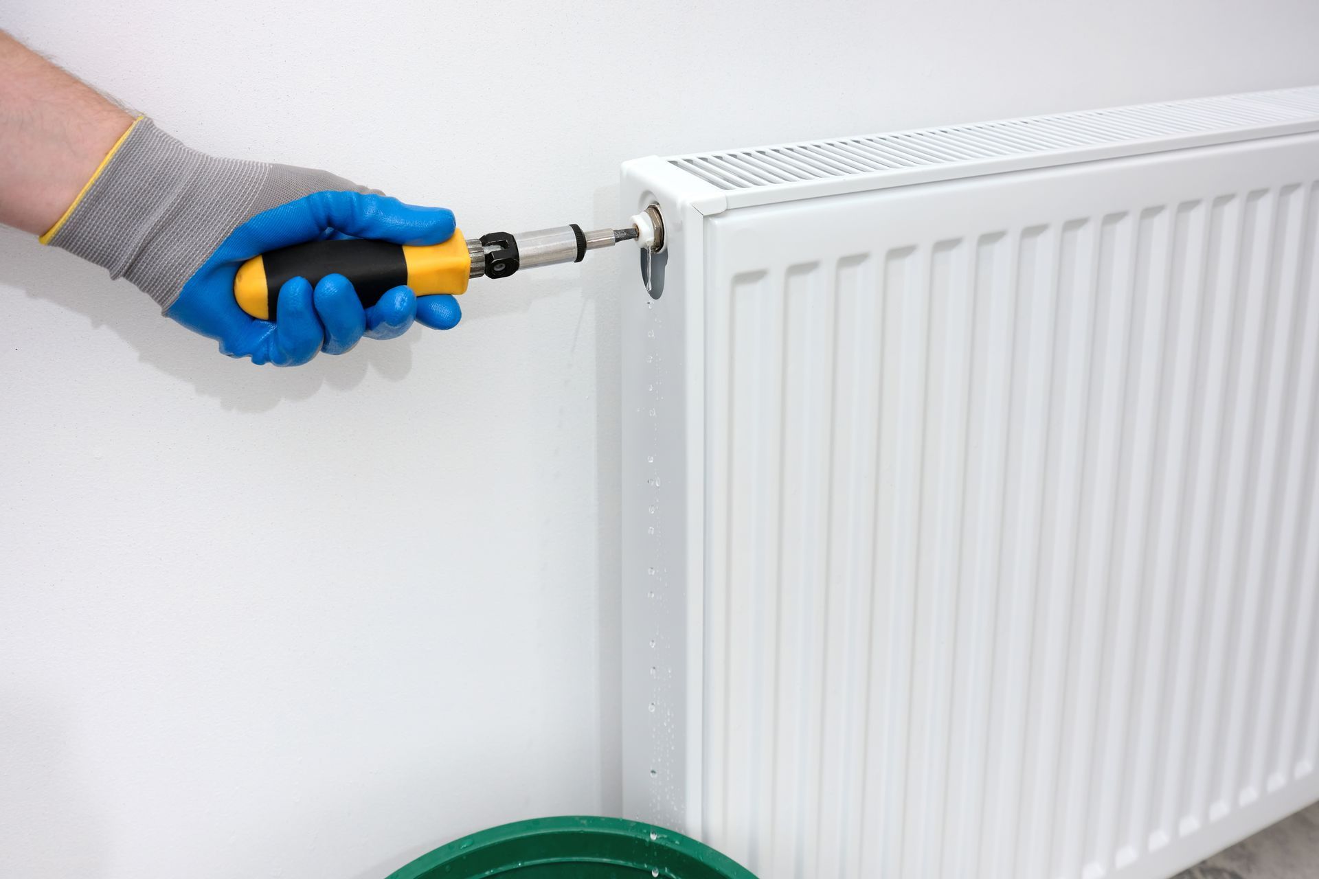 Una persona está arreglando un radiador con un destornillador.