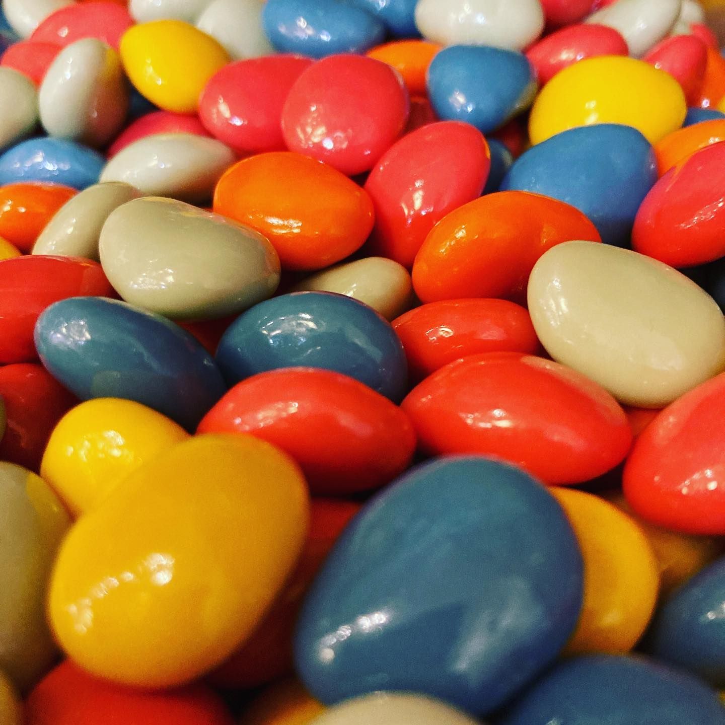 Bonbons colorés et brillants dans différentes nuances : rouge, jaune, bleu, orange et blanc.