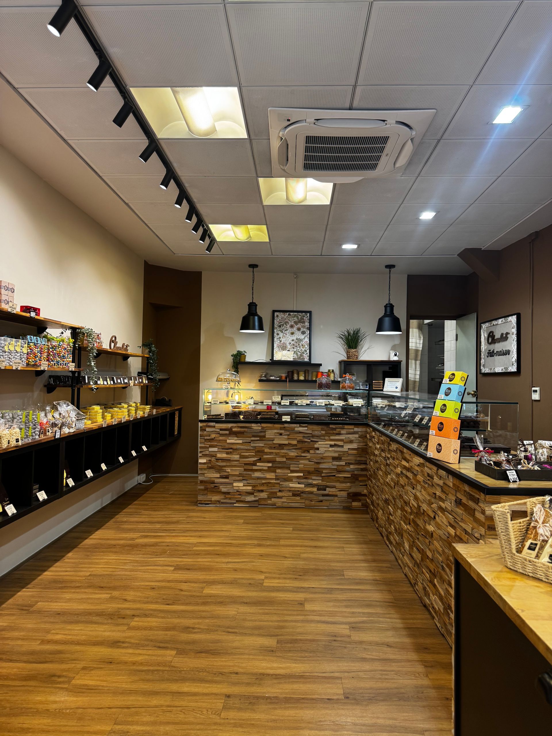 Intérieur du magasin avec des étagères de produits à gauche, un comptoir de bonbons et du parquet.