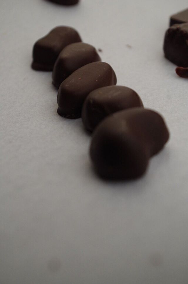Cinq bonbons au chocolat noir alignés sur une surface blanche.