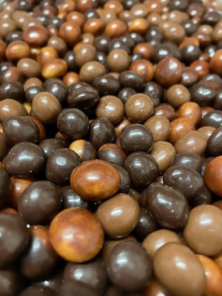 Gros plan d'un assortiment de bonbons enrobés de chocolat dans des tons de brun et de beige.