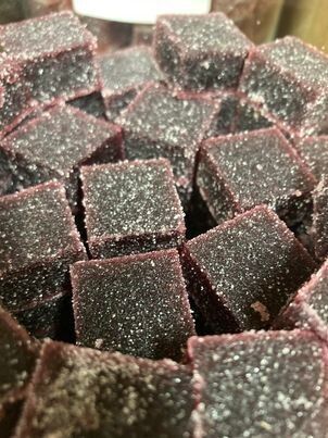 Pâtes de fruits violet foncé recouvertes de cristaux de sucre, empilées les unes sur les autres.