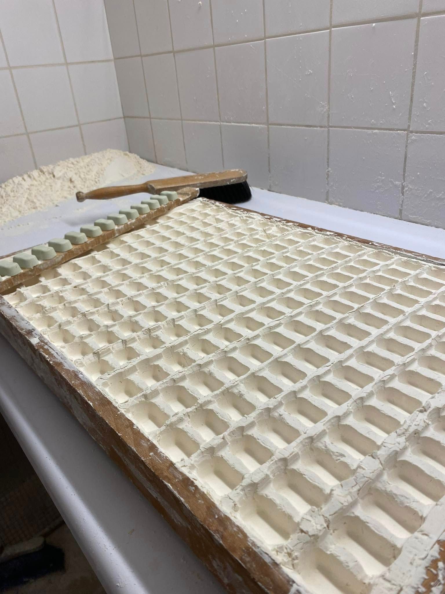 Moule en bois rempli de farine, utilisé pour former de petites formes rectangulaires dans un cadre de cuisine.