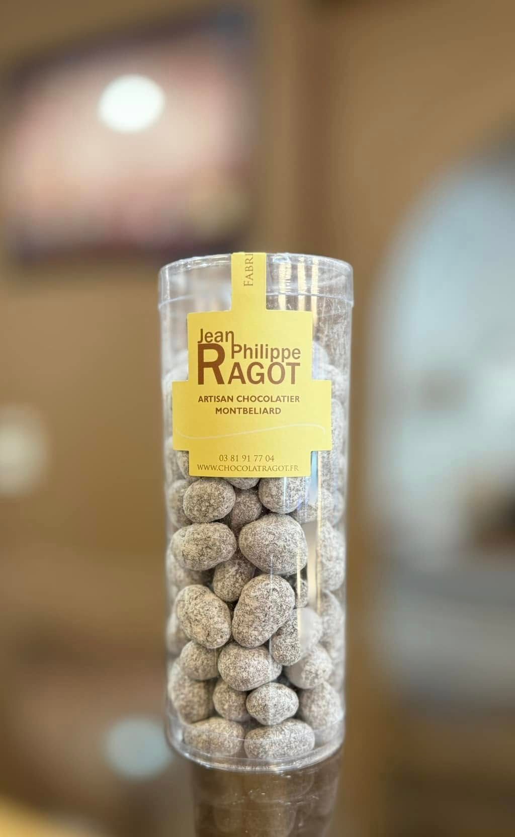Récipient en plastique transparent rempli de dragées, étiqueté Jean-Philippe Ragot.