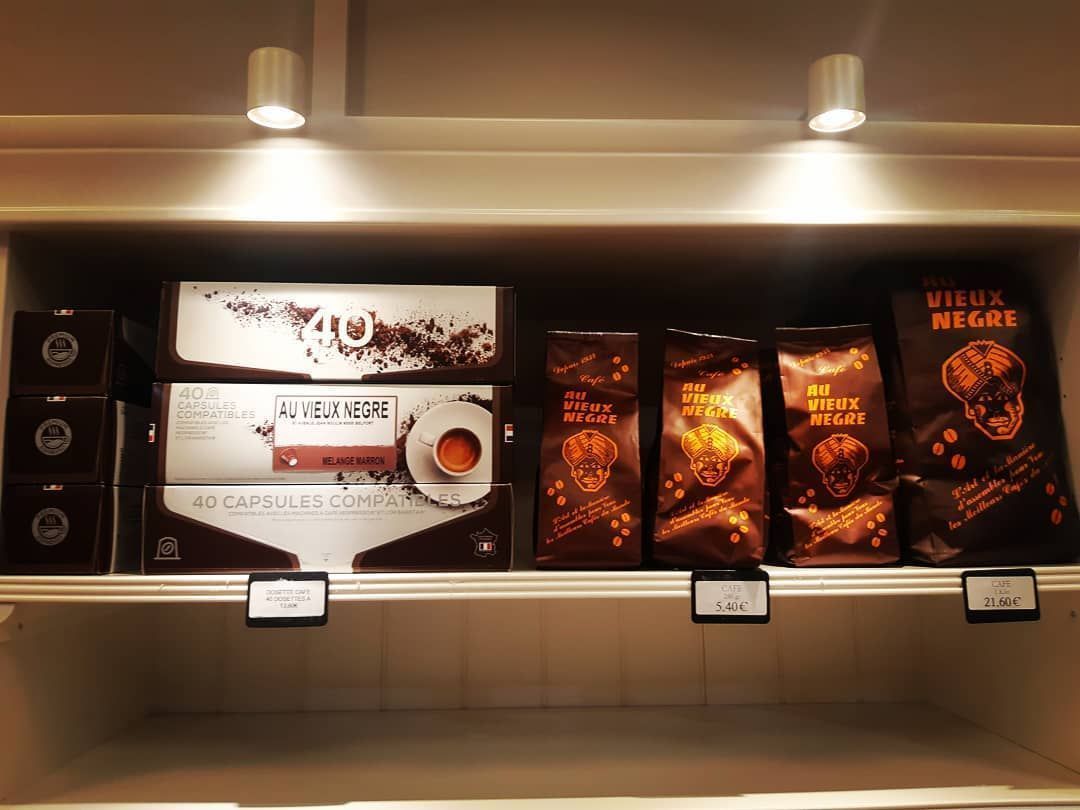 Des étagères remplies de divers produits de chocolat brun, dont des boîtes et des sacs, sous des lumières blanches.