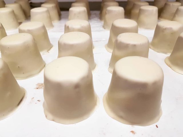 Bonbons blancs de forme conique disposés en rangées, peut-être une chaîne de production.
