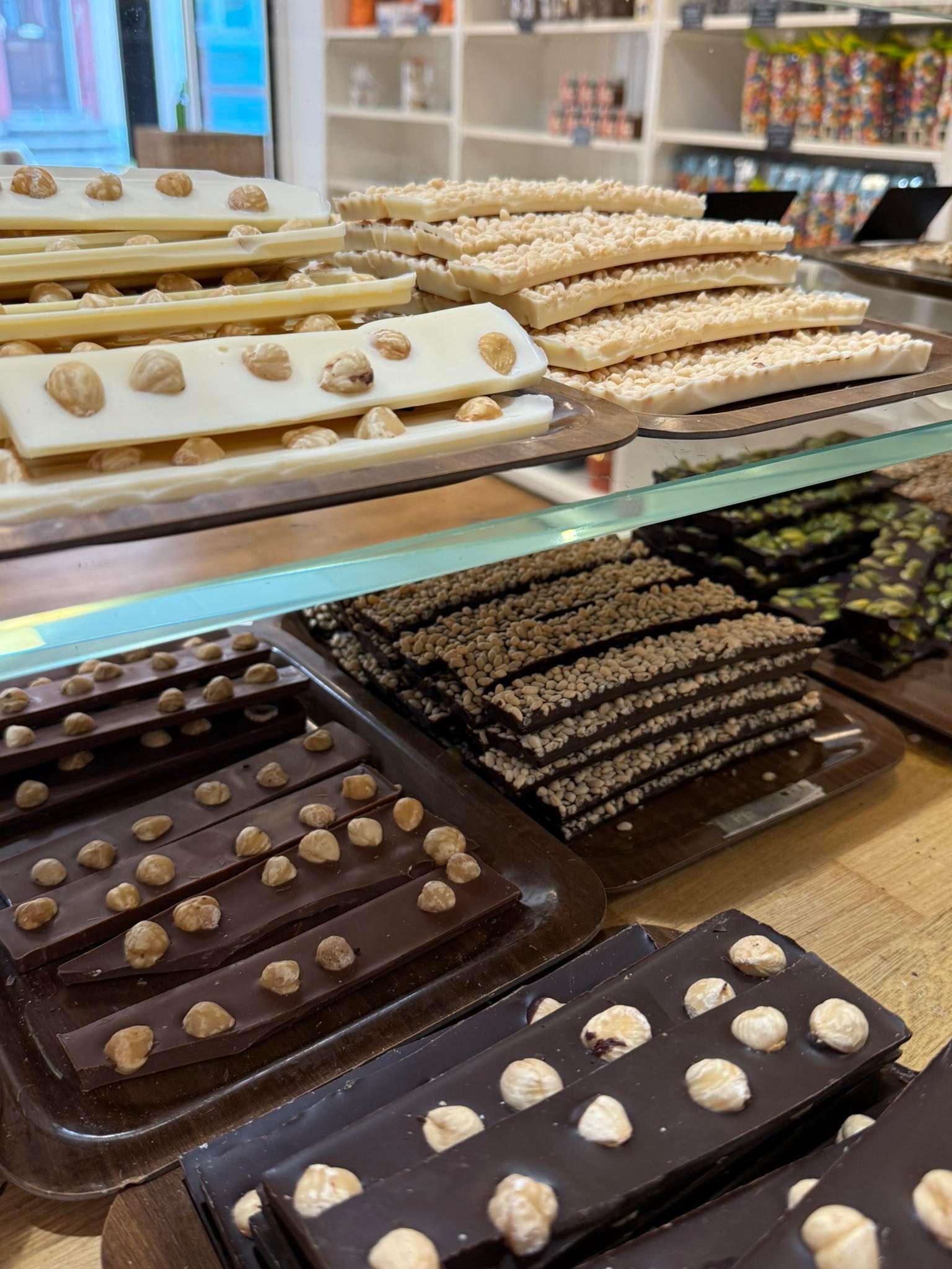 Gros plan d'une vitrine remplie de diverses barres de chocolat garnies de noix et de graines.