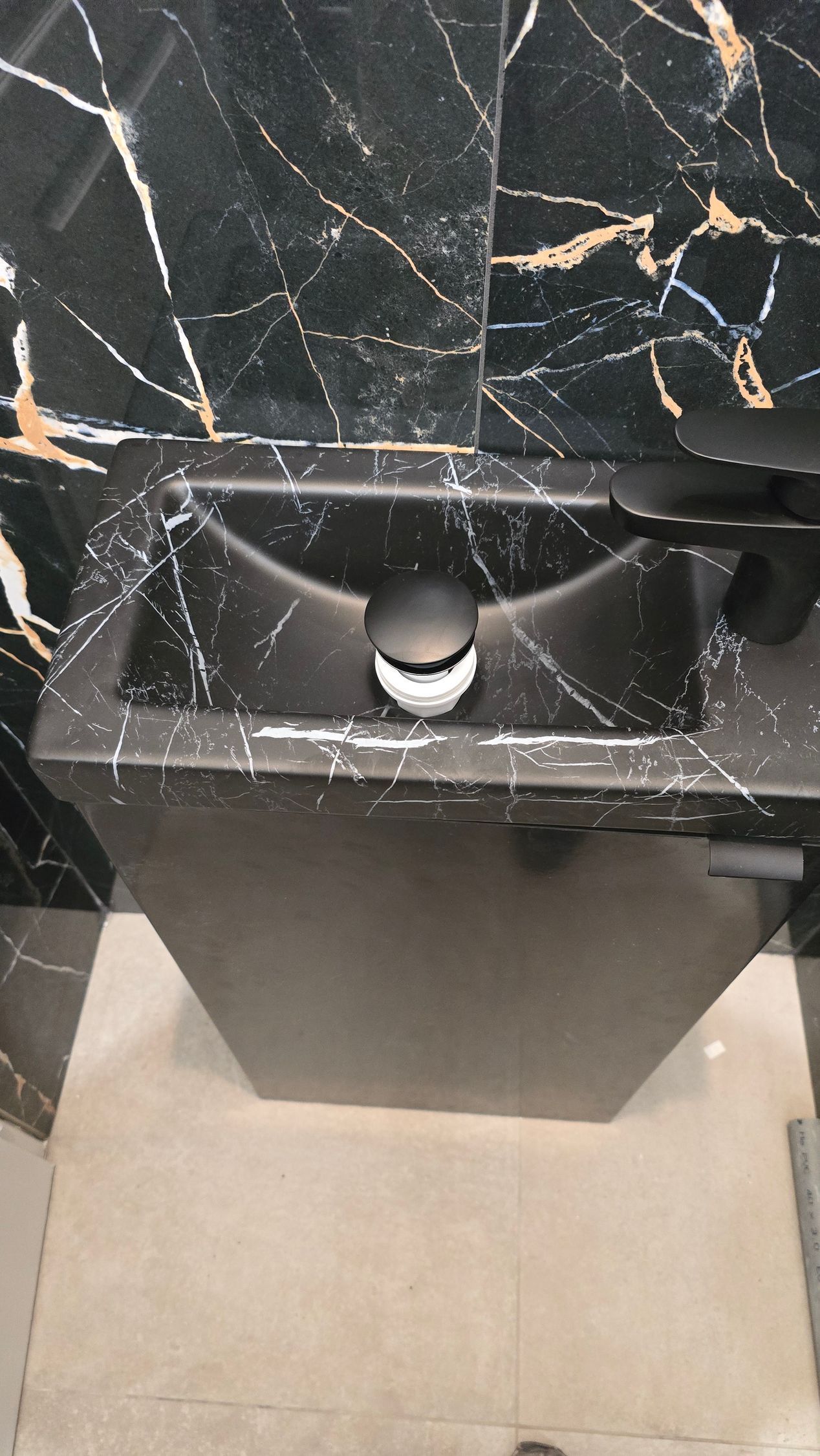 Lavabo de salle de bains en marbre noir avec robinet chromé au-dessus d'un sol carrelé beige