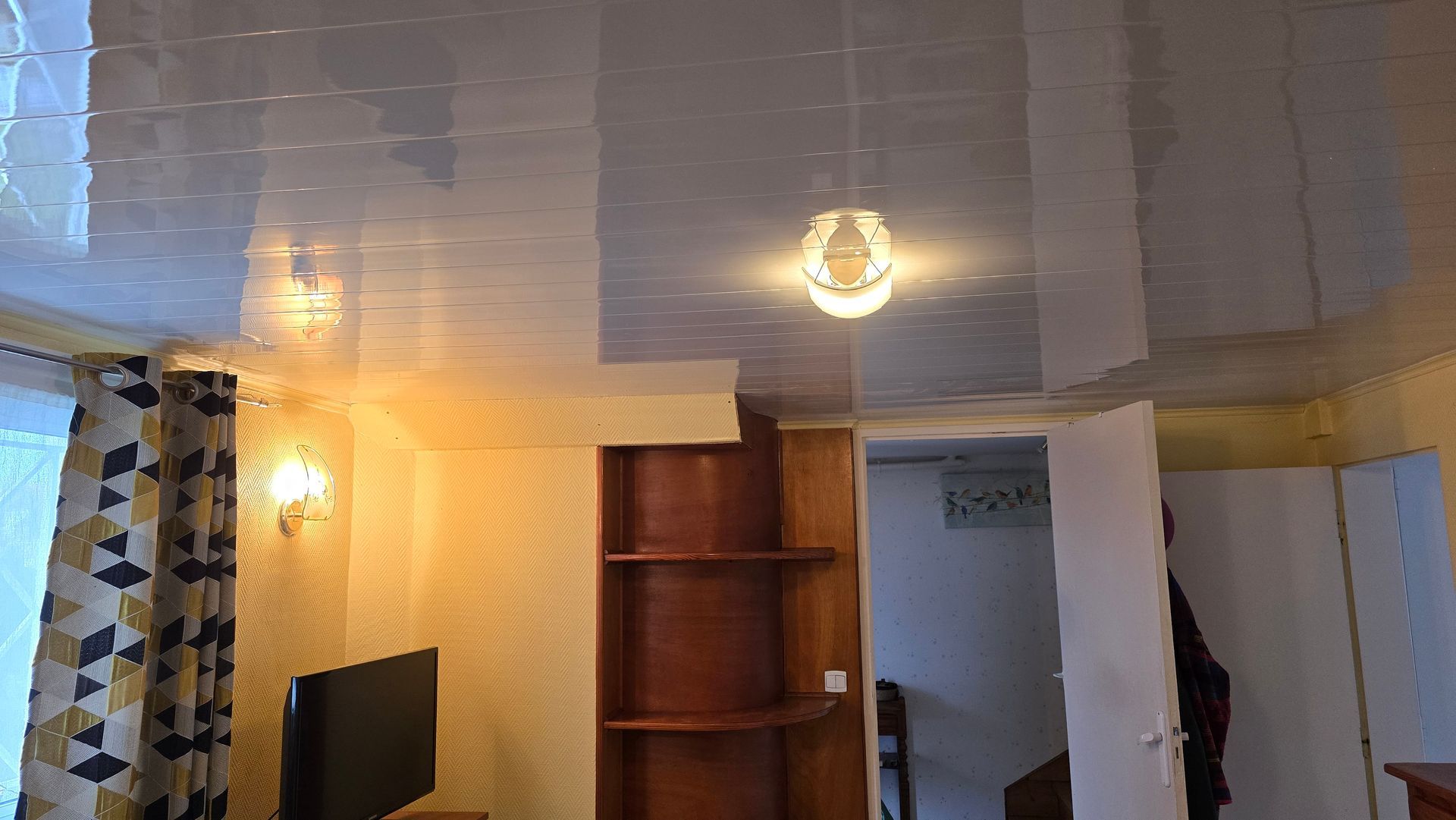 Intérieur moderne d'une chambre avec plafond blanc, éclairage chaleureux, étagère en bois.