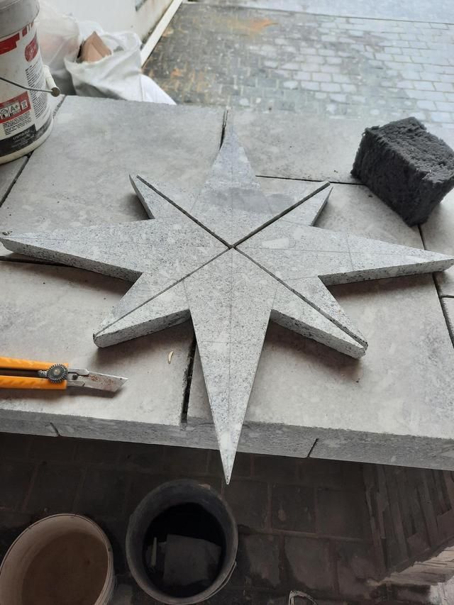 Découpe en forme d'étoile dans une pierre grise posée sur un établi, avec un couteau utilitaire et une éponge noire.
