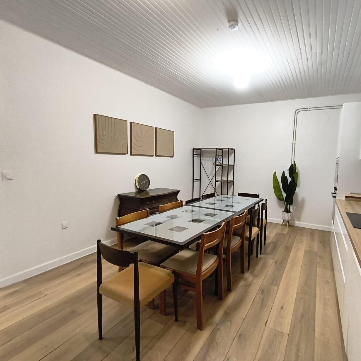 Salle à manger moderne avec une grande table, des chaises noires sur un parquet clair.