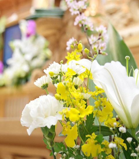 Un ramo de flores amarillas y blancas con hojas verdes.