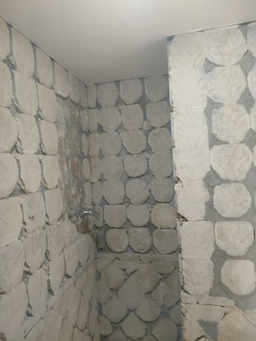 Un baño con pared de piedra y ducha.