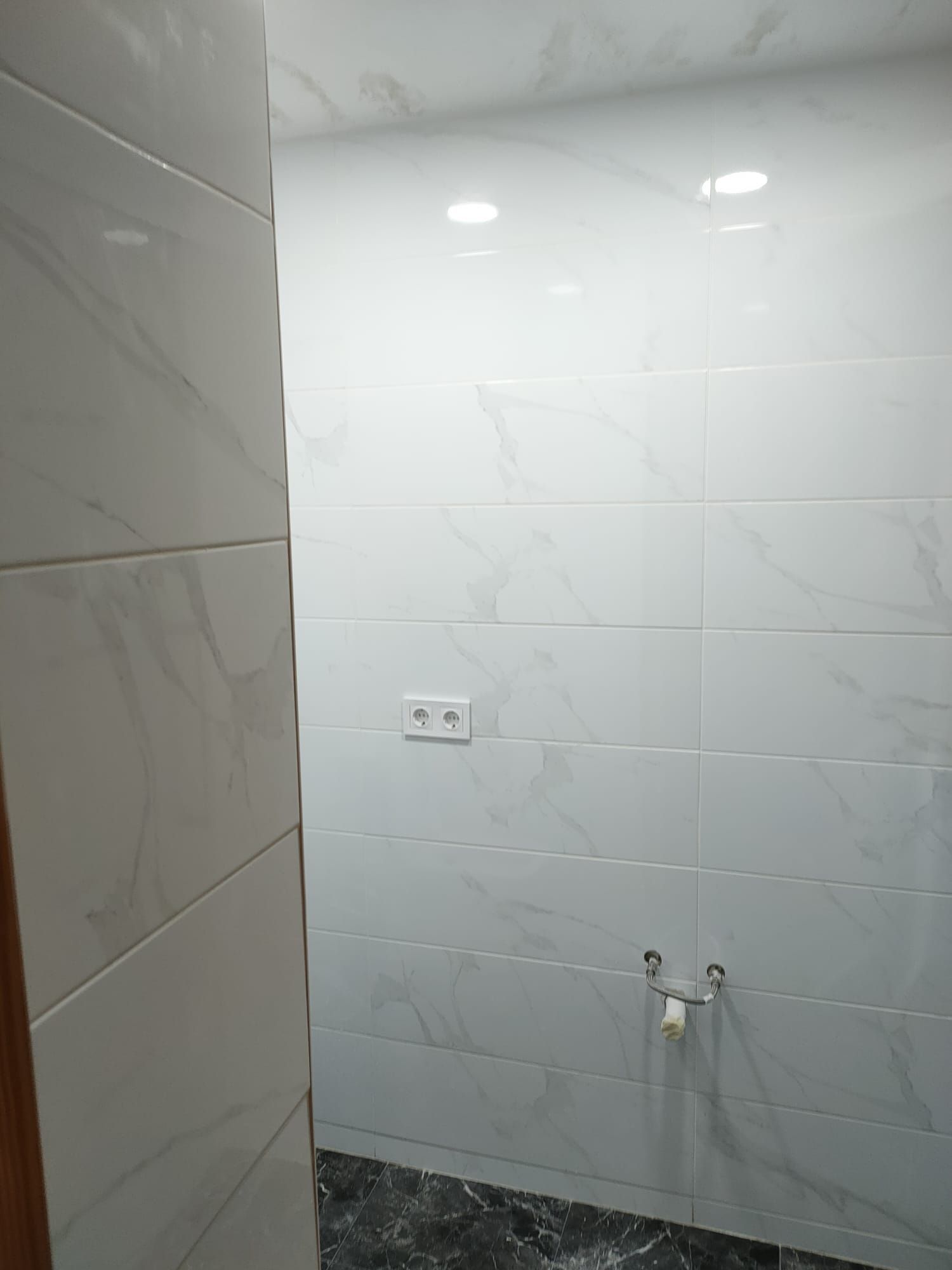 Un baño con azulejos blancos y suelo negro.