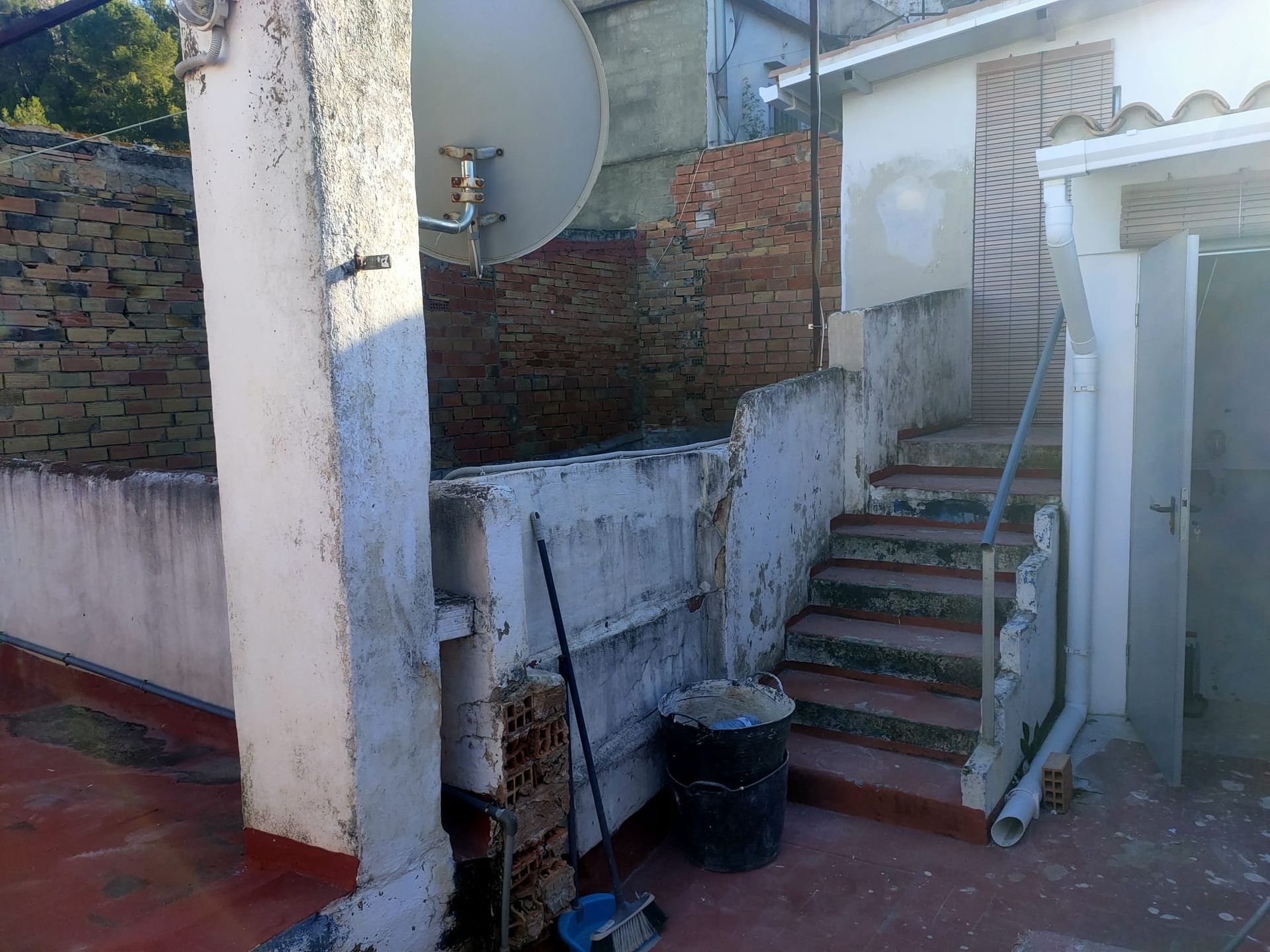 Escaleras que conducen a un edificio con una antena parabólica en la pared.