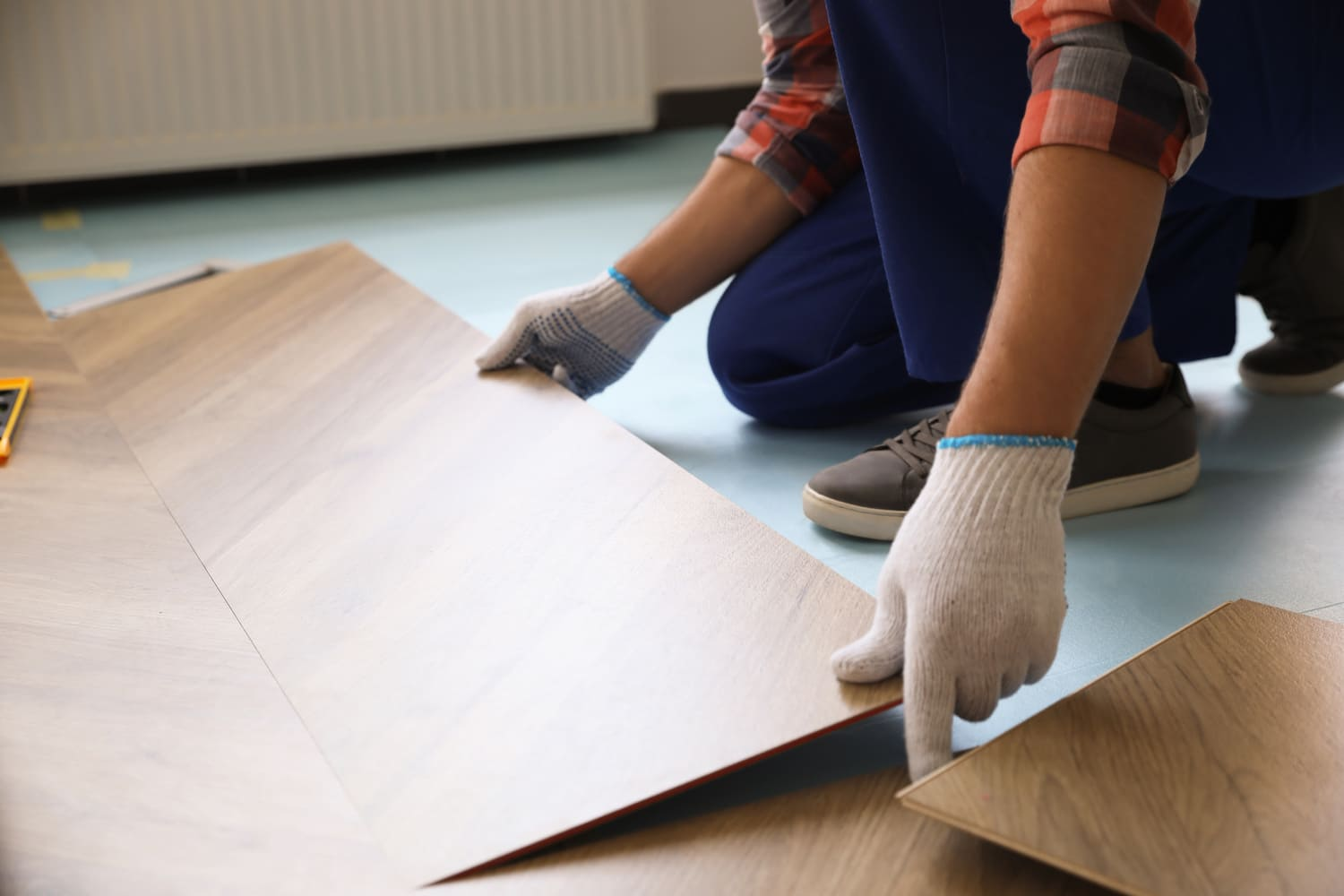 Una persona está instalando un piso de madera en una habitación.