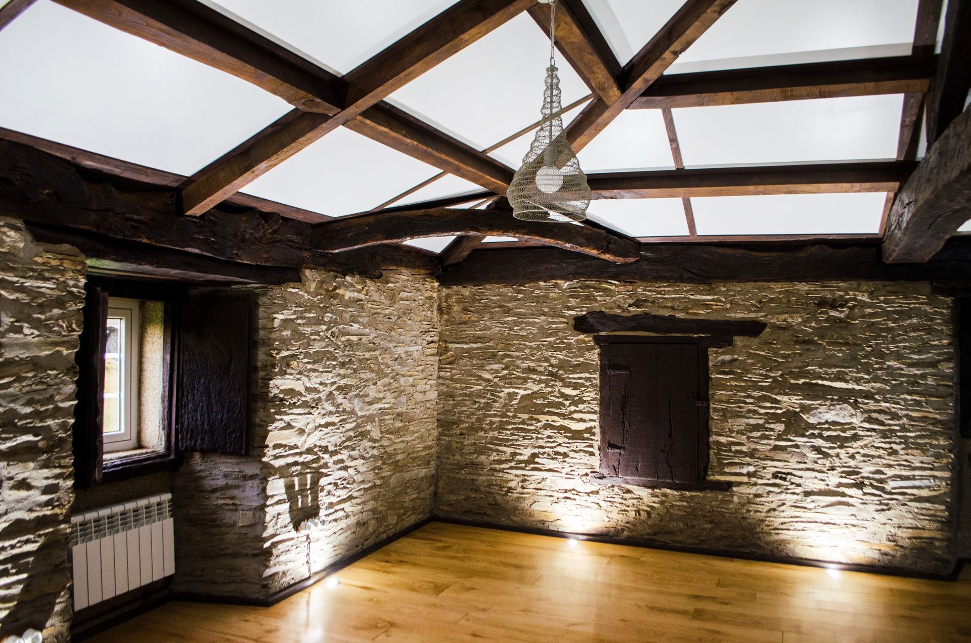 Una habitación vacía con suelo de madera y paredes de piedra.