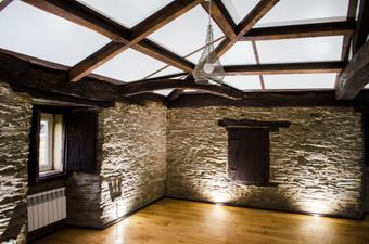 Una habitación vacía con suelo de madera y paredes de piedra.