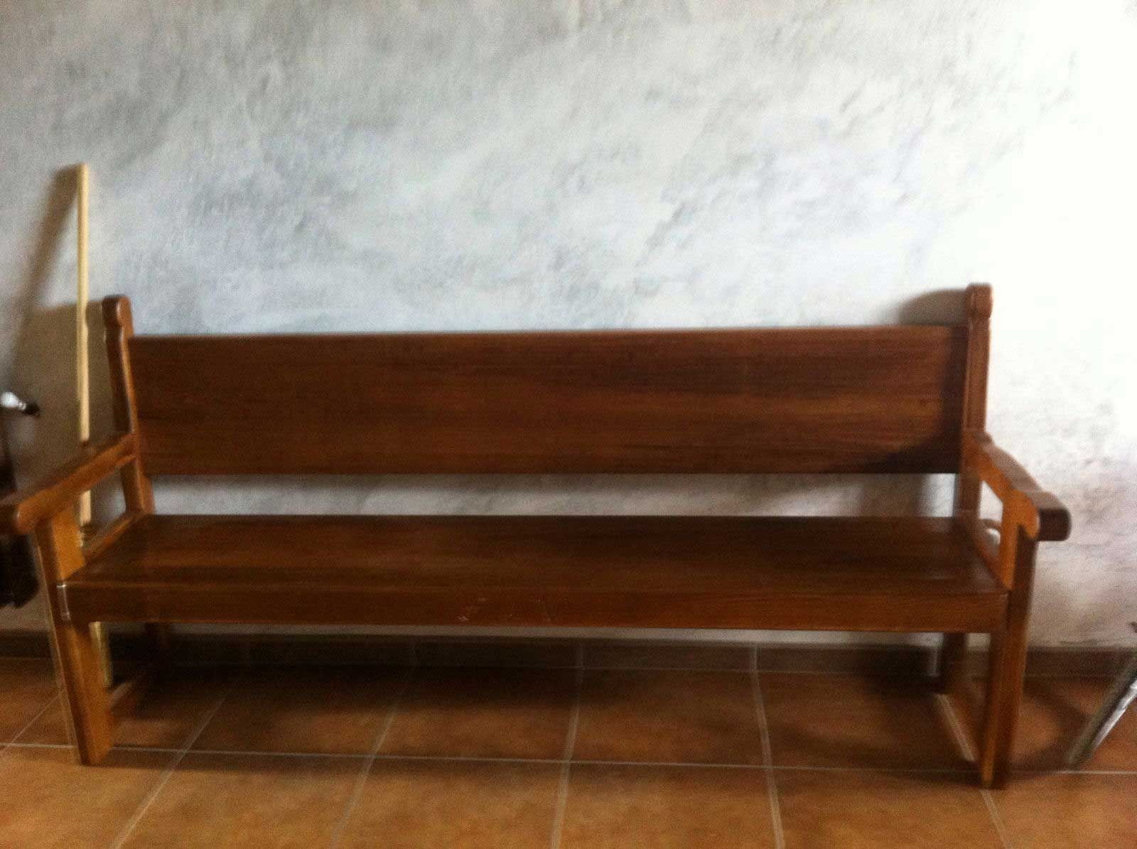Un banco de madera está sentado frente a una pared blanca.