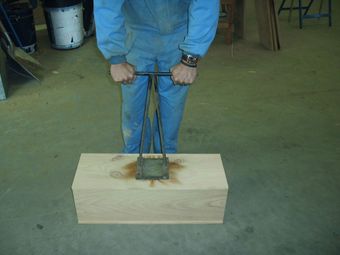Un hombre sostiene una herramienta sobre una caja de madera.