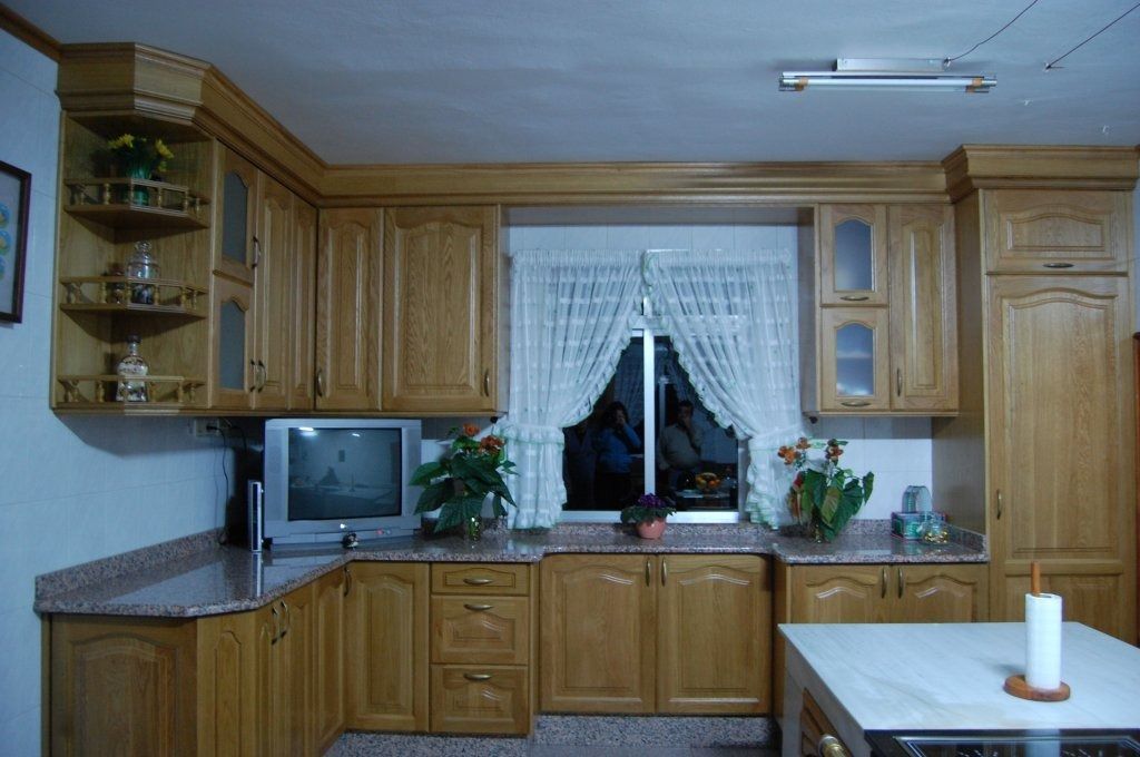 Una cocina con gabinetes de madera y un televisor de pantalla plana.