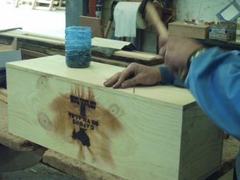 Una persona está martillando una caja de madera que tiene la palabra 